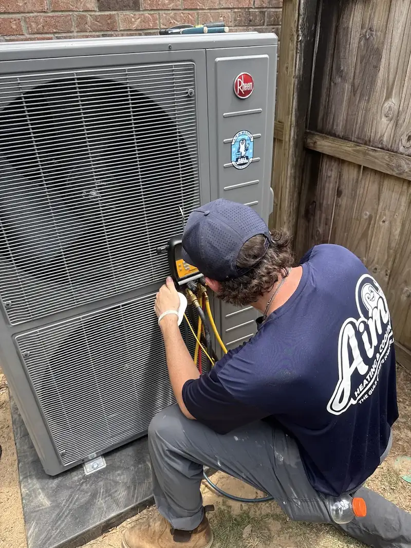 AIM technician using diagnostic gauges beside an outdoor unit