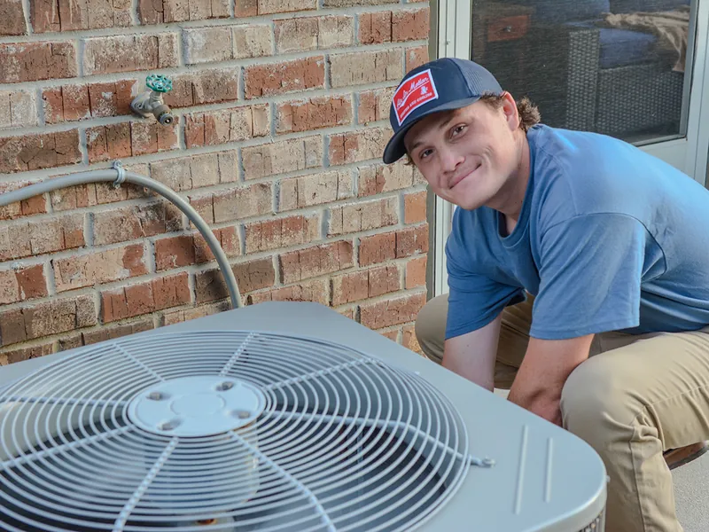AIM technician beside an outdoor air-conditioning unit
